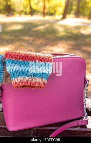 A striped knitted sock sticks out from a stylish women's handbag. Woolen socks. Exclusive hand-knitted items. Warm homemade clothes. Natural materials Stock Photo