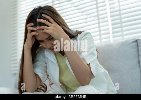Headache, female having migraine pain, bad health, Asian woman feeling stress and headache, Office syndrome, sad tired touching forehead having migrai Stock Photo