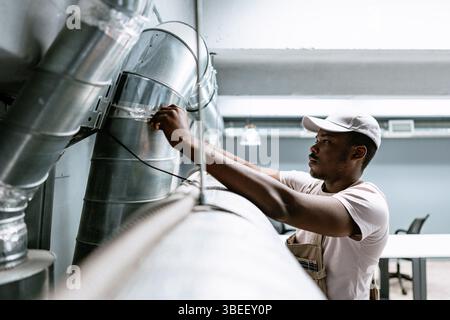 Technician working on ventilation system in modern office during daytime Stock Photo