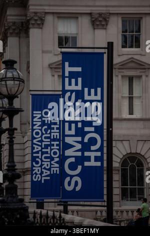 Blue banners at Somerset House display cultural messaging in London. Visible are historic architectural elements and street lamps. Stock Photo