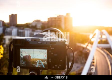 Professional photography with a camera on a tripod photographing an urban cityscape against the sun in sunset for a hobby concept Stock Photo
