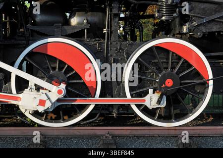 Red and white wheels and piston of an old steam engine train Stock Photo