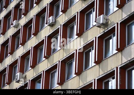 Facade of an old soviet residential, office building with repetitive pattern of windows, many featuring air conditioning units. Stock Photo