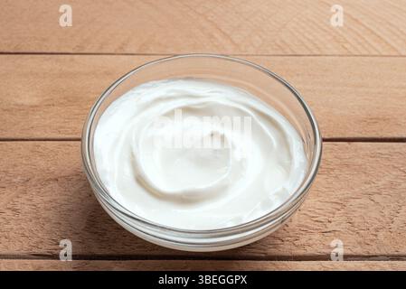 Bowl of Greek Yogurt on wooden background close up. Homemade sour cream or yogurt, healthy eating ingredient. Stock Photo