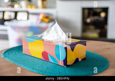 Colorful tissue box with white tissue paper on a wooden table indoors Stock Photo