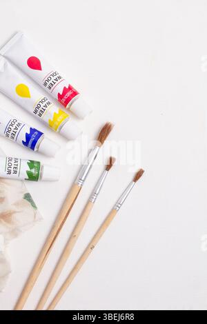 Three paintbrushes and watercolor bottles on a white background with copy space in a top view Stock Photo