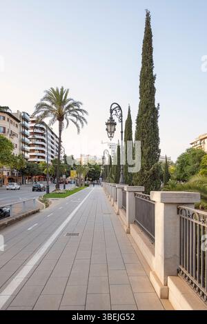 Urban pedestrian walkway near a water channel featuring a decorative stone wall with wrought iron fence in a quiet residential neighborhood Stock Photo