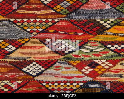 Background of a traditional Moroccan Berber rug featuring an intricate geometric pattern of diamonds and wave motifs in lovely colors Stock Photo