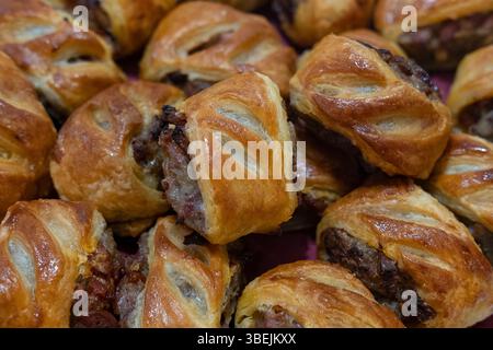Freshly baked sausage rolls made with golden, flaky puff pastry and filled with seasoned meat mixture, a classic homemade snack popular as appetizers Stock Photo