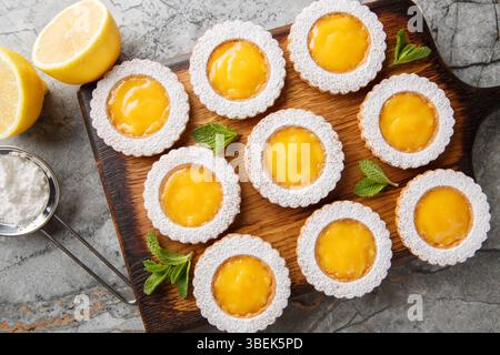 Lemon Curd Cookies feature a soft and buttery lemon cookie filled with a bright citrusy homemade lemon curd closeup on wooden board on the table. Hori Stock Photo