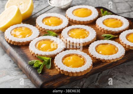 Lemon Curd Cookies feature a soft and buttery lemon cookie filled with a bright citrusy homemade lemon curd closeup on wooden board on the table. Hori Stock Photo