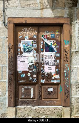 Stickers posters and graffiti tags on old wooden door, Guimaraes, Portugal, Europe Stock Photo