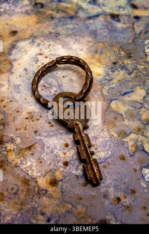An aged key lies on a beautifully textured surface, showcasing its unique design and patina. Stock Photo