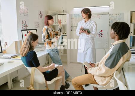 Group of students discussing ideas in well-lit, contemporary office environment. Diverse team engaging in creative brainstorming session Stock Photo