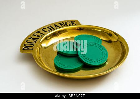 Brass Pocket Change tray with a pile of poker chips on a white background. Stock Photo