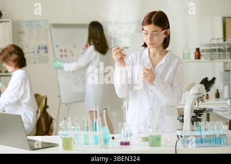 Researchers in white lab coats conducting experiments in chemistry lab. Student preparing chemical solution Stock Photo