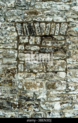 Vertical Canadian  historic gray stone wall close-up with bricked-in window from the 1800's Stock Photo