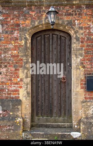 Old rustic wooden door, brick wall, and overhead lantern. Stock Photo