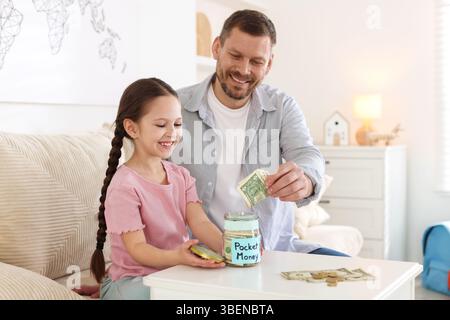 Father giving his daughter pocket money at table indoors Stock Photo
