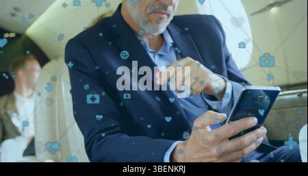 Network of digital icons floating against caucasian businessman using smartphone in a plane Stock Photo