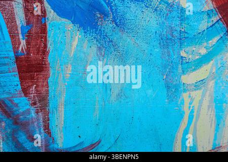 Messy multicolor brush strokes. Light blue, red, white, blue paint drips, flows, streaks on wall outdoors Stock Photo
