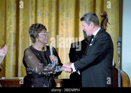 Ella Fitzgeralnd shaking hands with President Ronald Reagan after performing in the White House on 13th October 1981. Ella Jane Fitzgerald (April 25, 1917 – June 15, 1996) was an American singer, songwriter and composer, sometimes referred to as the "First Lady of Song", "Queen of Jazz", and "Lady Ella". She was noted for her purity of tone, impeccable diction, phrasing, timing, intonation, absolute pitch, and a "horn-like" improvisational ability. Stock Photo
