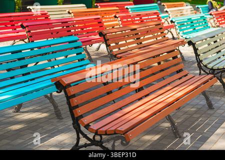 Row of multi colored benches. Colorful wooden benches arranged in rows outdoors, creating lively playful atmosphere in urban park. Concept of color Stock Photo