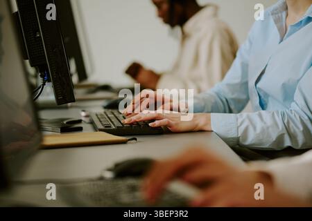 Busy office scene with employees working on computers, collaborating on projects. Focus on two individuals engaged in professional tasks. Background s Stock Photo