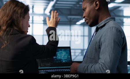 Software developers using AI tech on laptop in data center managing server virtualization. IT expert coding on notebook in server room using artificial intelligence, finetuning network, camera A Stock Photo