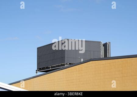 Large air conditioning unit on the roof of a building against a blue sky background Stock Photo