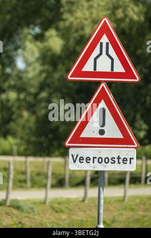 Poederoijen, Gelderland, Netherlands, Red triangular warning road signs indicating a narrowing road and a cattle grid, in a rural area Stock Photo