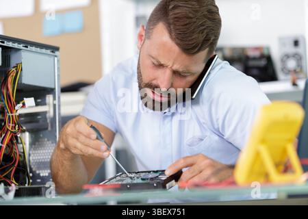 an engineer on the phone repairs a pc computer Stock Photo