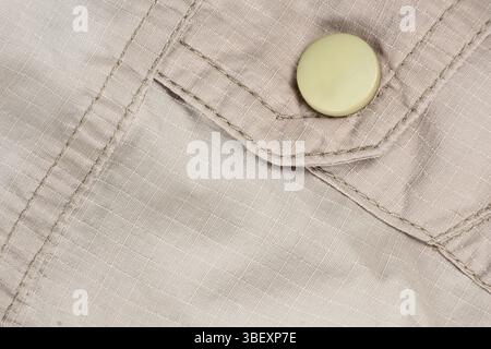 Macro beige clothing, stitched fabric and button Stock Photo
