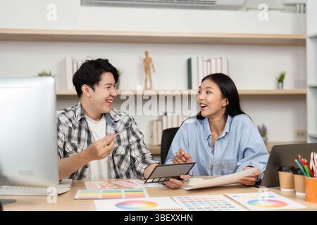 UX and UI Design Teamwork. Young designers sharing insights on color schemes and layouts in an office setting. Stock Photo