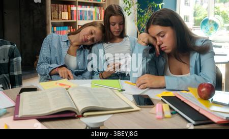 Four lazy napping stressed overload overworked tired students pupils classmates teenagers sleeping exhausted preparing to exams difficult education in Stock Photo