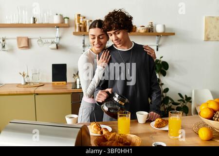 A couple shares breakfast and coffee in their bright kitchen, embracing warmly. Stock Photo