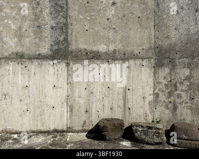 Concrete wall with rough texture, small holes and stains, close-up industrial surface in daylight, abstract background for design or construction. Stock Photo