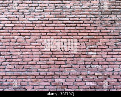Old red brick wall with rough texture and uneven pattern, close-up, daylight, abstract construction background for design, architecture or restoration Stock Photo