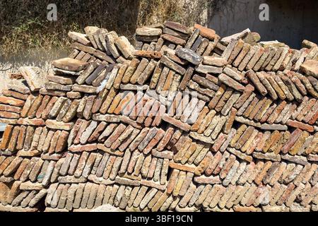 Stack of old clay bricks in irregular pattern, construction material background, building industry texture, rustic surface, no people. Stock Photo