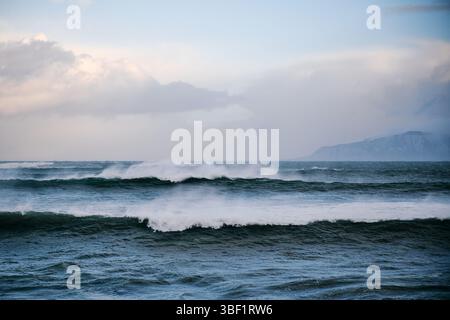 Strong wind forming big waves in the ocean with island in background Stock Photo