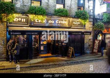 People enter "The Quays Bar" in Dublin, Ireland, for live music and Guinness. The bar is open late, offering a lively atmosphere. Stock Photo