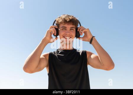 Happy Young Man with Headphones Enjoying Music Outdoors Stock Photo