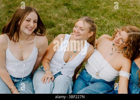 University students wearing white tops and denim jeans on grass Stock Photo