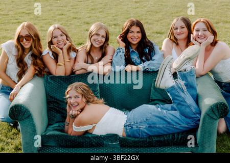 Generation z university students posing on green sofa outdoors Stock Photo