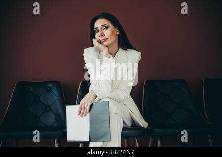 Pensive young businesswoman sitting and waiting during a recruitment process in a professional setting Stock Photo