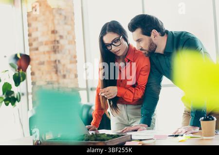 Two professionals collaborating in an office setting, reviewing business plans and discussing ideas for a project in progress Stock Photo