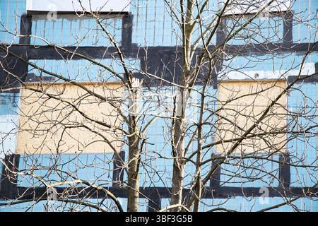 Boarded up windows of a multi-story building after a missile strike in Dnipro, Ukraine, aftermath of destruction and terror against a tree background Stock Photo