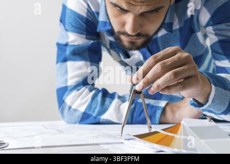 Man measuring with compass divider on construction blueprint. Architect workplace with technical drawing. Architecture studio concept with design proj Stock Photo