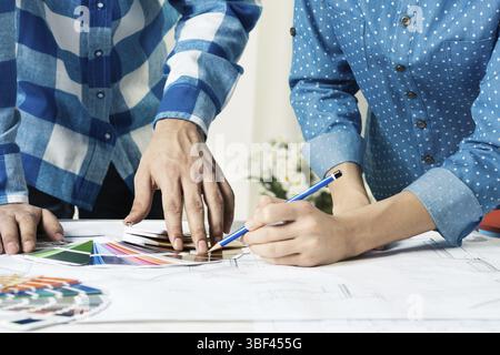 Designers selecting color palette for design project. Human hands, technical drawing and color swatches on desk. Interior design, decoration and renov Stock Photo