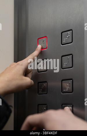 Close-up of a finger pressing several elevator buttons, highlighting the metallic texture and the moment of interaction in a modern lift panel. Stock Photo
